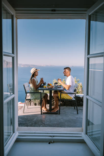 istock couple having breakfast at traditional cave house Santorini Greece, beautiful whitewashed village Oia with church and windmill during sunset 1269378740