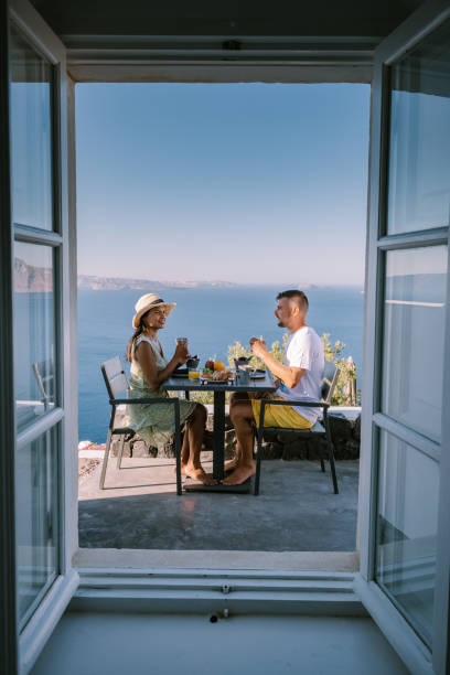 istock couple having breakfast at traditional cave house Santorini Greece, beautiful whitewashed village Oia with church and windmill during sunset 1269379867