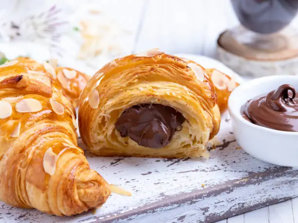 Photo of Yummy freshly croissant, sliced almonds, with chocolate filling cut, close up