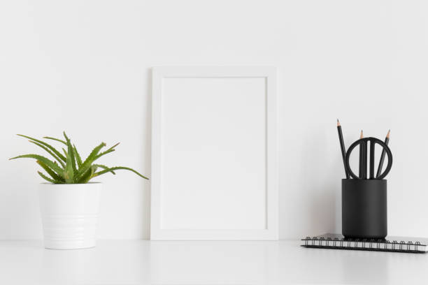 istock White frame mockup with a succulent plant and workspace accessories on a white table. Portrait orientation. 1269393723
