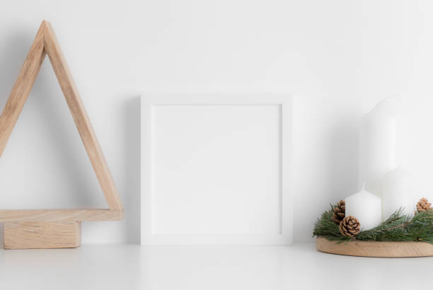 istock White square frame mockup with a wooden tree and candles on a white table. Christmas decoration. 1269394041