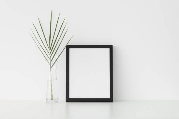 istock Black frame mockup with palm leaf in a glass vase. Portrait orientation. 1269394192
