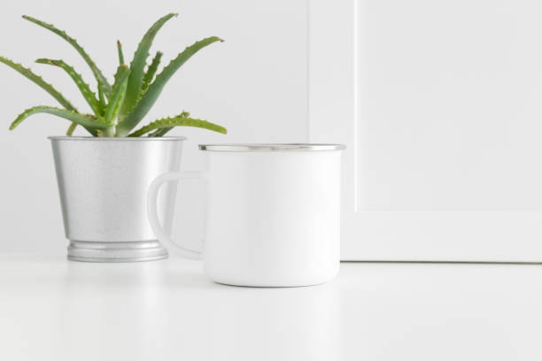 istock Enamel mug mockup with workspace accessories and a succulent plant on a white table. 1269394754
