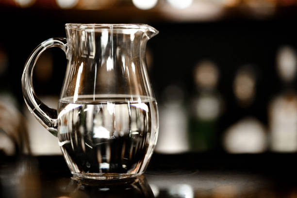 Glass jug of water on dark background. Space for text