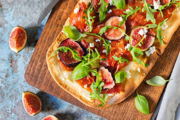 Homemade pizza with figs, prosciutto,arugula and goat cheese Homemade pizza with figs, prosciutto,arugula and goat cheese flatbread stock pictures, royalty-free photos & images