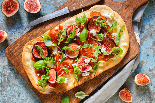 Homemade pizza with figs, prosciutto,arugula and goat cheese