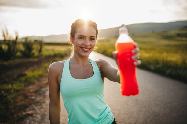 Time for refreshment Attractive young blonde sportswoman is refreshing with cold drink after jogging in nature on sunny summer day at sunset energy drink photos stock pictures, royalty-free photos & images