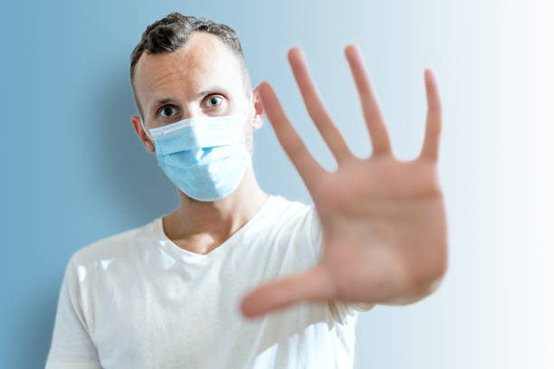 istock young man in medical mask shows open palm stop gesture on blue background 1269414628