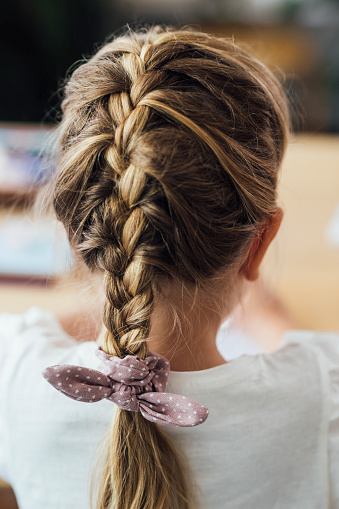 Back view of a blonde girl with a braid, a close up.