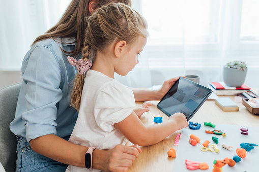 Boosting children's creativity: happy woman playing with her daughter at home.