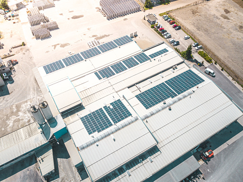 Aerial view of solar panels installed as shade roof over parking lot with parked cars for effective generation of clean electricity. Photovoltaic technology integrated in urban infrastructure.
