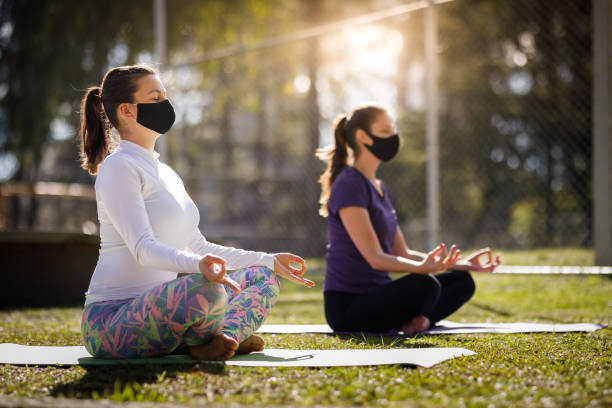istock Women meditating on town square wearing face mask 1269422365