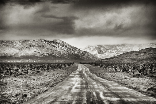A long straight road leading to some mountains through the desert of Nevada in the United States.