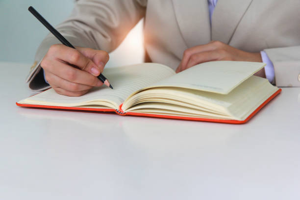 istock Woman hand is writing on a notebook with a pencil in office. 1269425781