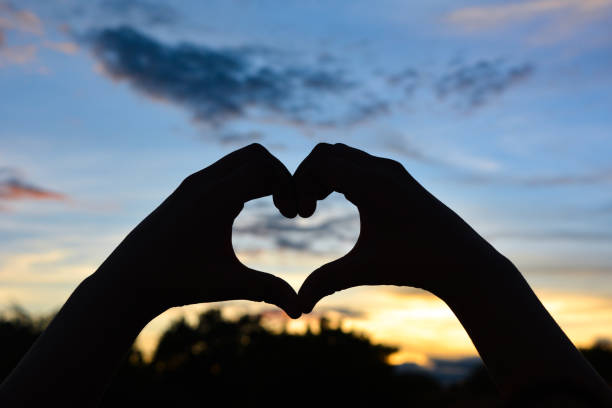 istock Silhouette hand in heart shape with sunset 1269437261