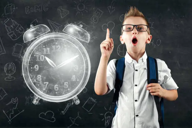 Time management concept, schoolboy with a backpack and near the image of an alarm clock. Time is fleeting, dead line, the passage of time, children's time. Copy space