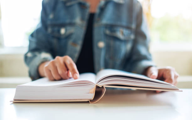 istock a woman sitting and reading book at home 1269440152