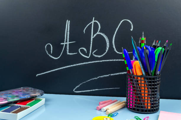istock School supplies on a blue table, in the back a black chalkboard with letters 1269443220
