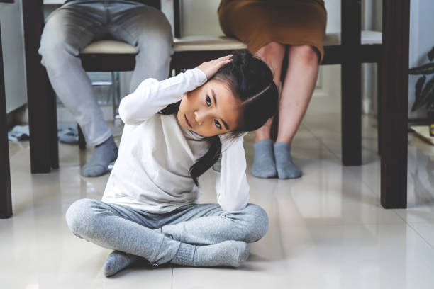 asian little daughter sad and clog the ears under table while parent quarrelling in kitchen, photo design for family problems and unhappy concept - two parent family indoors home interior domestic kitchen imagens e fotografias de stock