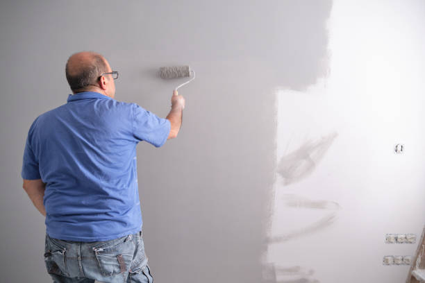 istock Real senior house painter painting a grey wall with a paint roller 1269449350