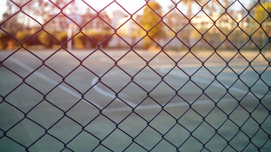 sport empty court with hard surface behind iron fence outside