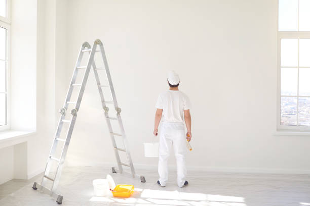istock A male painter in a white uniform with a roller works in his hand in a white room 1269457958