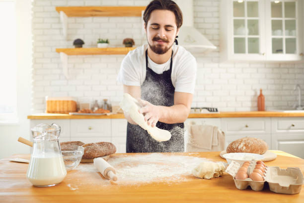 istock Baker male bearded man makes fresh bread dough at a table in the bakery kitchen. 1269457963