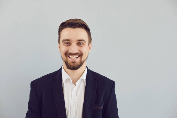 istock Positive bearded guy in a jacket smiling looks at the camera on a gray background. 1269458218