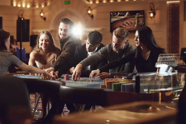 Photo of Group of friends bet at the roulette table in a casino.