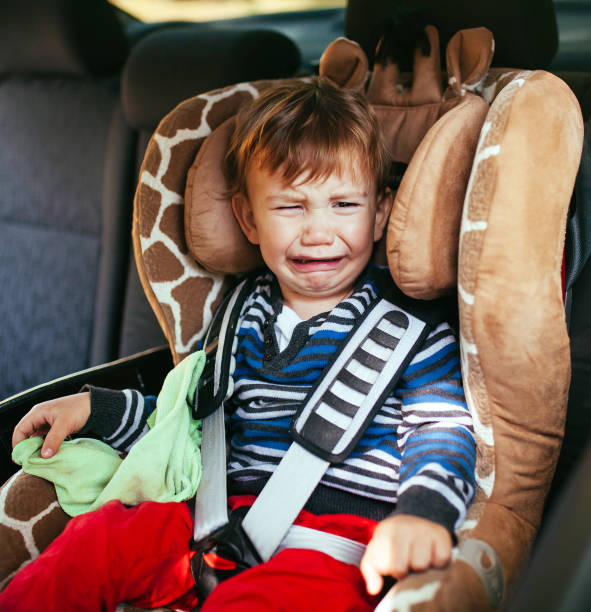 Crying baby boy in a safety car seat stock photo
