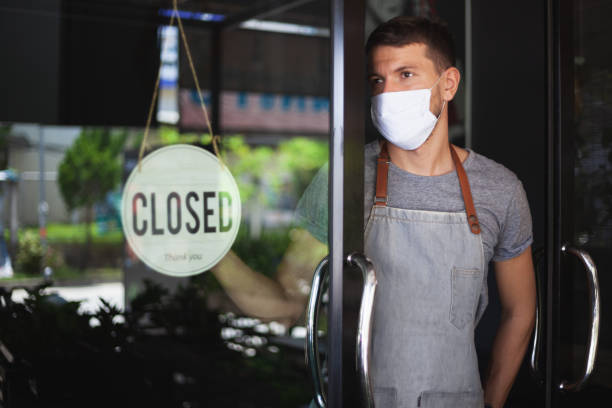 chef in maschera di sicurezza appeso cartello chiuso sulla porta del ristorante. - building exterior store closed photography foto e immagini stock