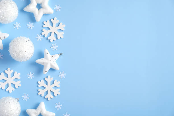 istock White Christmas decorations, balls, snowflakes, confetti on blue background. Flat lay, top view winter holiday background. Minimal style. 1269467792