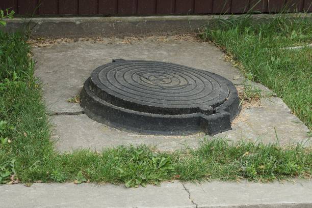 istock one black iron manhole on gray concrete in green grass 1269468471