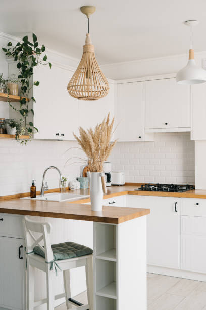 istock Modern white u-shaped kitchen in scandinavian style. Open shelves in the kitchen with plants and jars. 1269468853