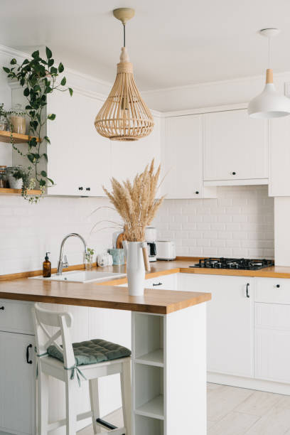 Modern white u-shaped kitchen in scandinavian style. Open shelves in the kitchen with plants and jars. stock photo