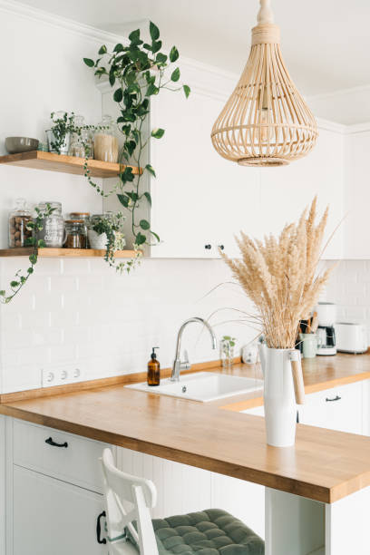 istock Modern white u-shaped kitchen in scandinavian style. Open shelves in the kitchen with plants and jars. 1269469452