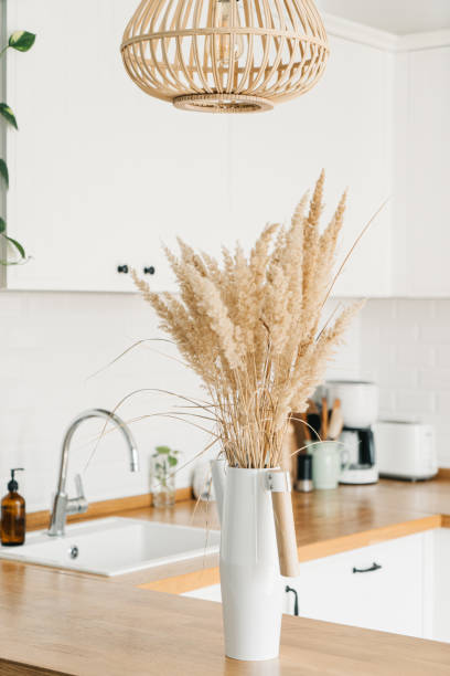 istock Modern white u-shaped kitchen in scandinavian style. Open shelves in the kitchen with plants and jars. 1269469459