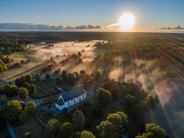 Aerial view over a church in Sweden. Morning fog above.