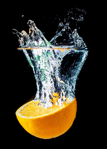 Close-up of oranges in water against black background.