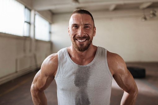 Portrait shot of a smiling muscly young man standing in the gym