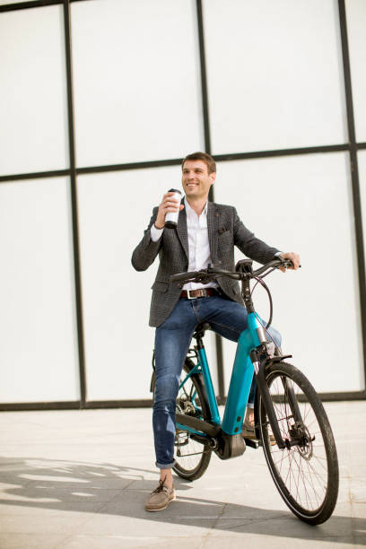 istock Young businessman on the ebike with takeaway coffee cup 1269475323