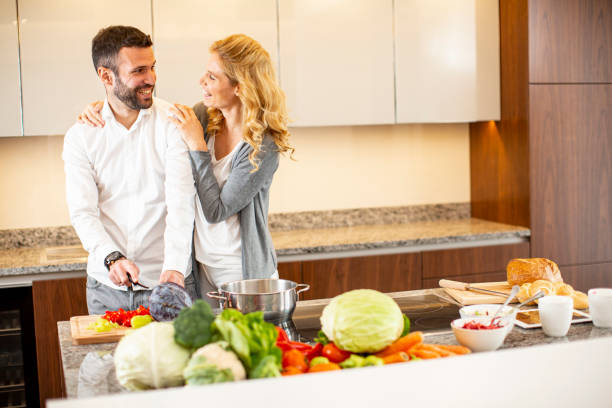 istock Young man helping his girlfriend cooking in the modern kitchen 1269475990