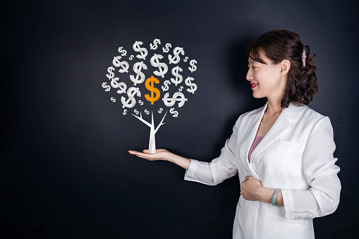 Asian woman and chalk money tree drawing on blackboard