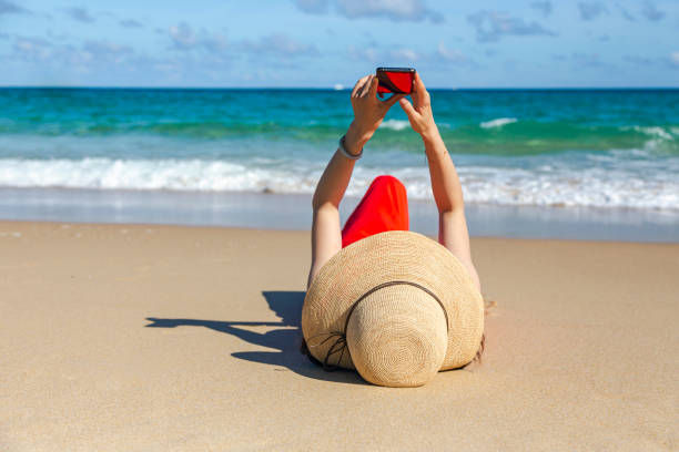 istock Female Enjoying and watching mobilephone on Beach 1269477605