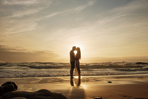 Silhouette of a couple kissing at a beach at sunset