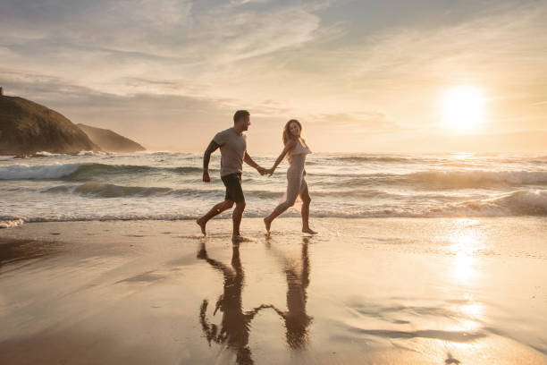 istock Young couple running barefoot on the beach 1269478466