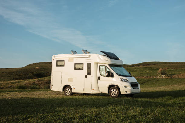 istock Motor home parked in a green field at sunset 1269478468