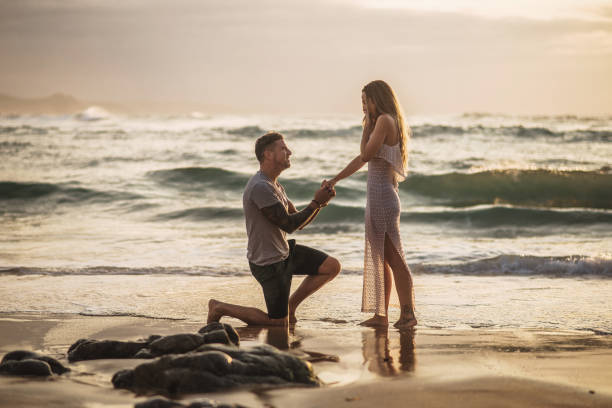 giovane che propone alla sua ragazza in spiaggia - engagement foto e immagini stock