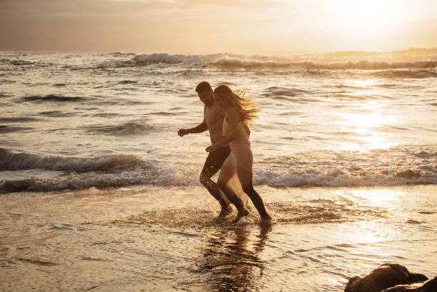 istock Young couple running barefoot on the beach 1269478603