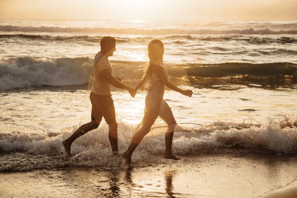 istock Young couple running barefoot on the beach 1269478749